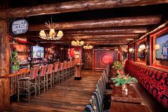 the bar is decorated with red and black chairs, wood floors, and chandeliers