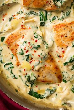 chicken with spinach and white sauce in a skillet on a red table cloth