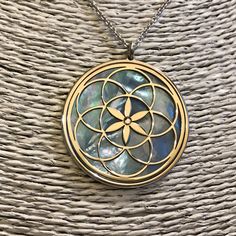 "Seed of Life in 925 silver, blue mother of pearl backdrop. The symbol commonly referred to as the Seed of Life is made up of seven circles; one in the center, and six others placed around it according to ancient spiritual traditions. It's tought that the seven interlocking circe are compared to the seven days of creation, with the different circles being ascribed to different points in the universe's making. The flore blooming in the middle is considered the Consciousness of God. It's a very po Sterling Silver Medallion Necklace With Pearl Pendant, Spiritual Round Mother Of Pearl Necklace, Polished Mother Of Pearl Necklace For Gift, Spiritual Mother Of Pearl Pendant Necklace, Pearl Pendant Medallion Necklace In Mother Of Pearl, Mother Of Pearl Medallion Necklace With Pearl Pendant, White Gold Mother Of Pearl Pendant Necklace, White Gold Mother Of Pearl Round Necklaces, Spiritual Medallion Necklace With Pearl Pendant