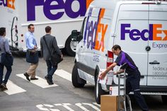 several fedex delivery trucks are parked on the side of the road with people walking by