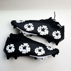 two black and white soccer shoes with flowers on the soles are laying on a table