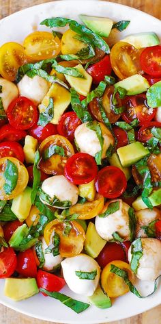 a white plate filled with lots of different types of vegetables on top of a wooden table