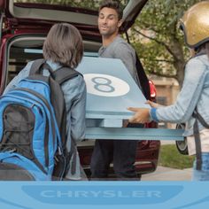 three people standing in front of a van with the number eight on it's back