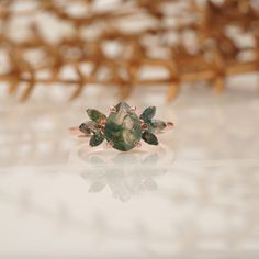 a ring with green leaves on it sitting on a table next to some flowers and branches