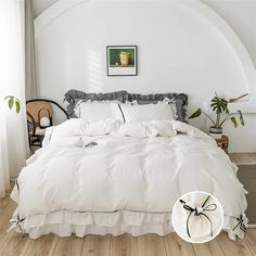 a large white bed sitting inside of a bedroom next to a chair and potted plant