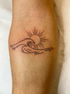 a tattoo on the leg of a person with a wave and sun in the background