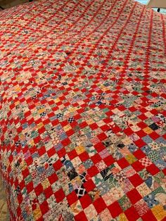 a red and white quilt on top of a bed in a room next to a window