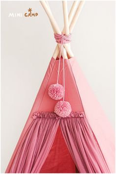 a pink teepee with pom poms hanging from it