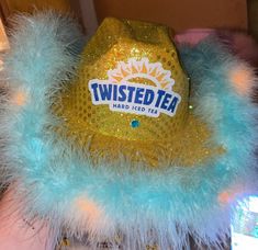 a teal and yellow hat with blue feathers on it that reads twisted tea hard iced tea