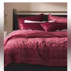 a bed with red sheets and pillows in a room