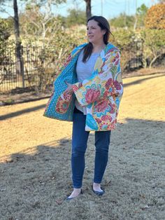 a woman standing in the grass with a colorful blanket