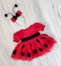 a red dress with black polka dots on it and a headband is laying on the floor