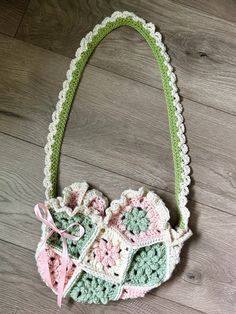 The handmade, crocheted, purse, has a coquette theme with its cite pink ribbon, ruched edges and pink, green and white floral pattern. 𝜗𝜚 ⊹  🐇 Pink Crochet Bag, Pink Crochet Purse, Crochet Flower Bag, Pink And Green Crochet Bag, Eco-friendly Pink Handmade Crochet Bag, Fairycore Crochet Bag, Flower Purses, Pink Outfits, Crochet Purses