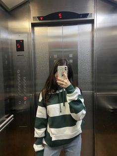 a woman taking a selfie in an elevator with her phone up to her ear