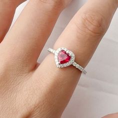 This lab-created ruby ring featuring a 6x6 mm heart shaped red ruby stone in the center. This heart ring is accented with 32 pieces of round shaped Moissanite stone around the center stone creating a beautiful halo design that enhances the center stone. The ring is carefully set in rhodium over 925 sterling silver. Elegant Red Heart-shaped Diamond Ring, Valentine's Day Gemstone Rings Fine Jewelry, Valentine's Day Gemstone Fine Jewelry Rings, Valentine's Day Fine Jewelry Gemstone Rings, Red Diamond Heart Ring Fine Jewelry, Red Heart Ring With Center Stone, Red Heart-shaped Rings With Center Stone, Valentine's Day Ruby Ring Fine Jewelry, Red Diamond Heart Ring For Anniversary