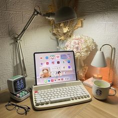 an open laptop computer sitting on top of a wooden desk next to a cup of coffee