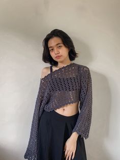 a woman standing in front of a wall wearing a cropped top and black skirt