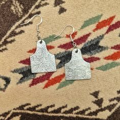 The classic, silver fashion of these earrings make them the perfect staple piece in your jewelry collection. Made of aluminum, they are very lightweight and easily worn. Due to the handcrafted nature of this item, the finished product may vary slightly from the photo. Silver Etched Metal Earrings, Etched Silver Metal Earrings, Stamped Metal Earrings For Gifts, Etched Metal Drop Earrings, Etched Metal Dangle Earrings, Cattle Tags, Country And Western, Engraved Earrings, Ear Tag