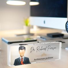 an office desk with a computer monitor and business card holder on it that says dr robert ferguson architecture professor