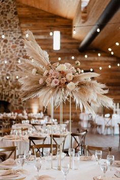 an elegant centerpiece with feathers and flowers is displayed in the middle of a banquet room