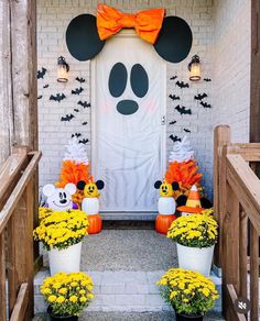 mickey mouse decorations on the front steps of a house with pumpkins and mumins