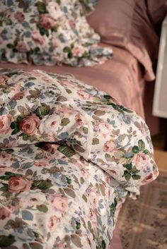 a bed with floral sheets and pillows on it