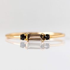 three stone ring in yellow gold with black diamonds on each side and two smaller stones at the top