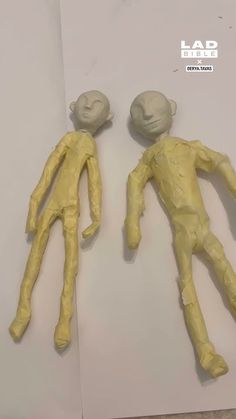 two fake human bodies sitting next to each other on top of a piece of paper