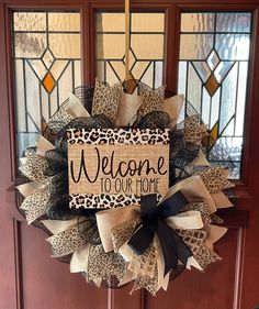 a welcome to our home wreath hanging on a door with leopard print and black ribbon