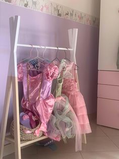 a child's bedroom with pink and green decor, including clothes on a rack