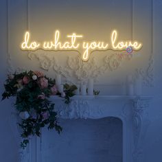 a neon sign that says do what you love on the wall above a fire place