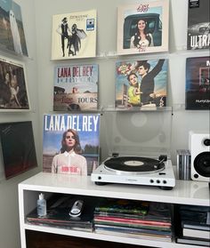 a record player sitting on top of a white shelf in front of a wall full of movies