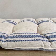 a blue and white striped pillow sitting on top of a wooden table