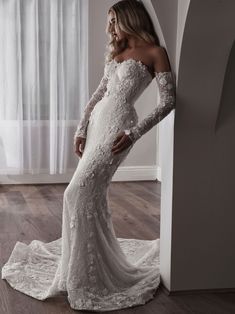 a woman in a white wedding dress leaning against a wall