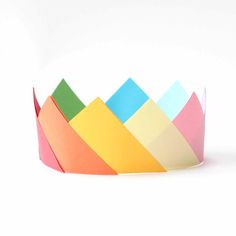 a paper crown is shown on a white background with the colors of the rainbow in it