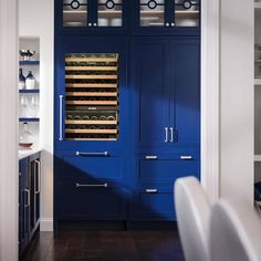 a kitchen with blue cabinets and white chairs