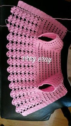 a pink crocheted purse sitting on top of a black bag