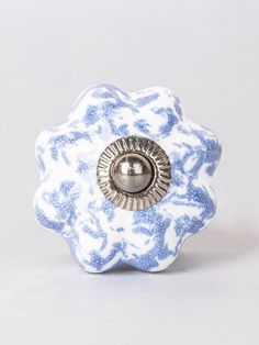 a blue and white flower shaped object with a metal button in the center on a gray background