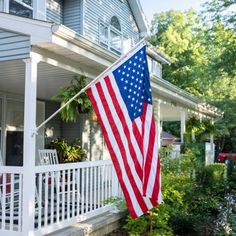 an american flag hanging on the front porch of a house