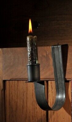 a candle that is on a hook in the wall next to a door handle with a leather strap hanging from it's side