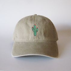 a baseball cap with a cactus embroidered on the front and back side, sitting on a white surface