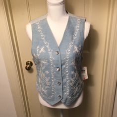 100% Cotton Shell With 100% Polyester Lining. Front Is Light Colored Denim With Beautiful White Embroidery And Pearlized Buttons. Back Is Blue And White Denim Stripes With Decorative Lower Back Belt Buckle That Can Be Adjusted. Size Small. Extra Buttons Included. Pet / Smoke Free Environment. Thanks For Shopping New And Like New! White Fitted Denim Vest, White Denim Top For Spring, Fitted Blue Cotton Denim Vest, Casual Embroidered Denim Vest For Spring, Summer Cotton Denim Vest With Floral Embroidery, Casual Embroidered Denim Vest For Summer, Summer Embroidered Blue Denim Vest, Embroidered Blue Denim Vest For Summer, Blue Embroidered Denim Vest For Summer