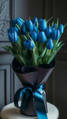 a bouquet of blue tulips in a vase with a ribbon tied around it