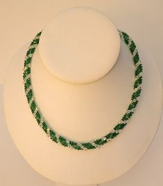 Handmade bead woven necklace in a Dutch Spiral pattern is made of emerald green and clear Swarovski crystals with a silver clasp. This necklace is fun, vibrant, and sparkles! It is the perfect necklace to dress up your outfit, especially during the holidays. This necklace has over 150 clear Swarovski crystals woven in a spiral pattern with sections of emerald green colored glass beads between them. This necklace weighs approximately 0.8oz and is approximately 19" in length from clasp to clasp. T Sparkling Green Crystal Jewelry, Green Crystal Beaded Necklaces As Gift, Green Crystal Beaded Necklace For Gift, Spiral Necklace, Woven Necklace, Spiral Pattern, Handmade Beads, Bead Caps, Organza Bags