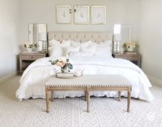 a bedroom with white bedding and flowers on the foot board in front of the bed