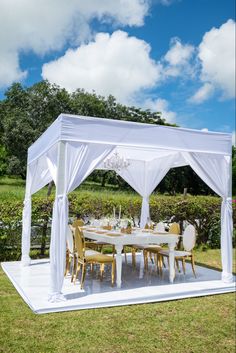 a white gazebo set up in the middle of a field with tables and chairs