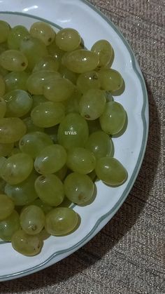 green grapes are in a bowl on the floor next to a brown carpeted area