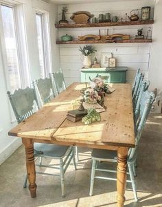 a wooden table surrounded by blue chairs in a room with open shelves on the wall