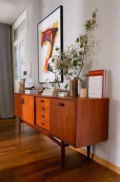 a wooden dresser sitting on top of a hard wood floor next to a white wall