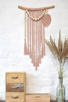 a vase with some flowers in it next to a wall hanging